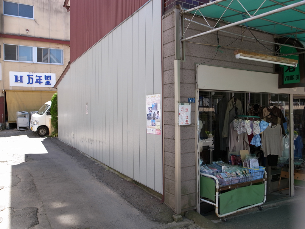 <b>奥の「万年堂」のロゴデザインも気になるが、手前の張り紙に注目……</b>