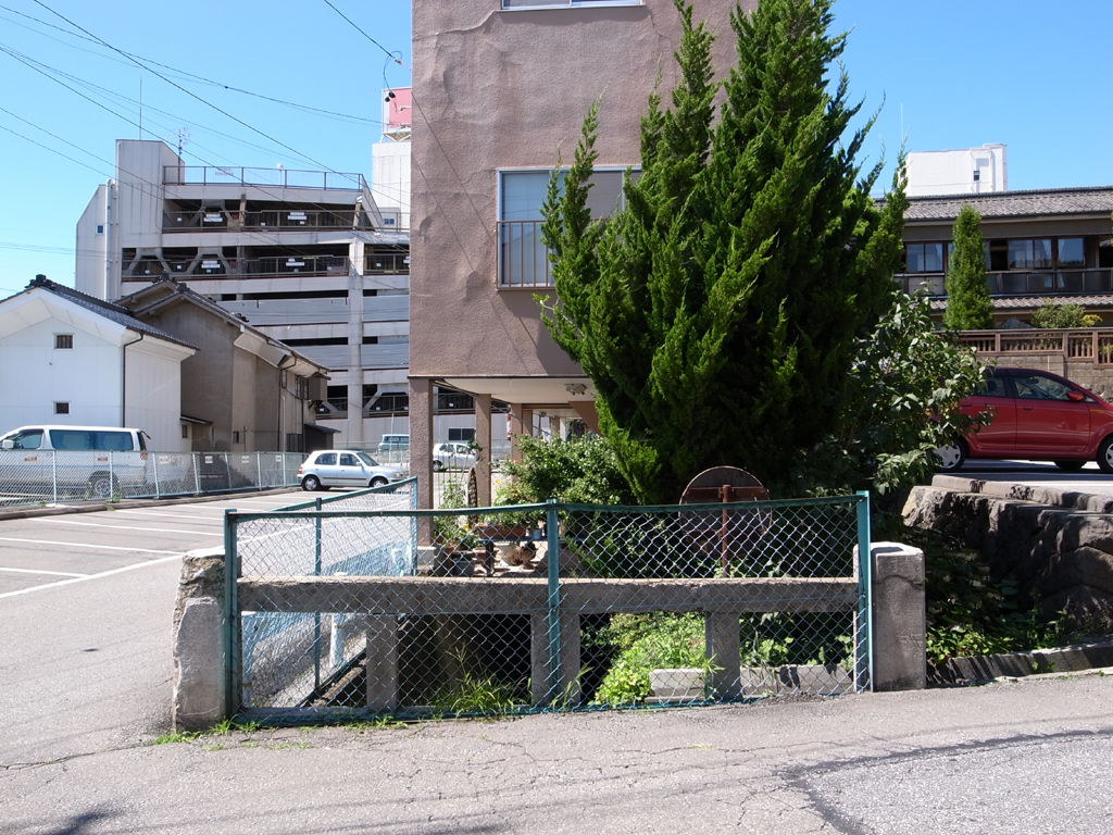 <b>焼肉屋さんの道路の向かい側を見てナットクしたのだが、石柱は橋の欄干だったのだ。つまり焼肉屋さんの真下には、川が流れているのだ</b>