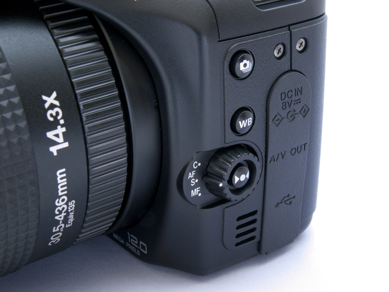 <b>左手側の横には「フォーカスモード切り換えレバー」が配置されている。このレバーを回してコンティニアスAFとシングルAF、そしてMFと切り換える。レバー中央のボタンは、MF時に使用するワンプッシュAF。その上に配置されているのが「ホワイトバランス」設定のボタン</b>