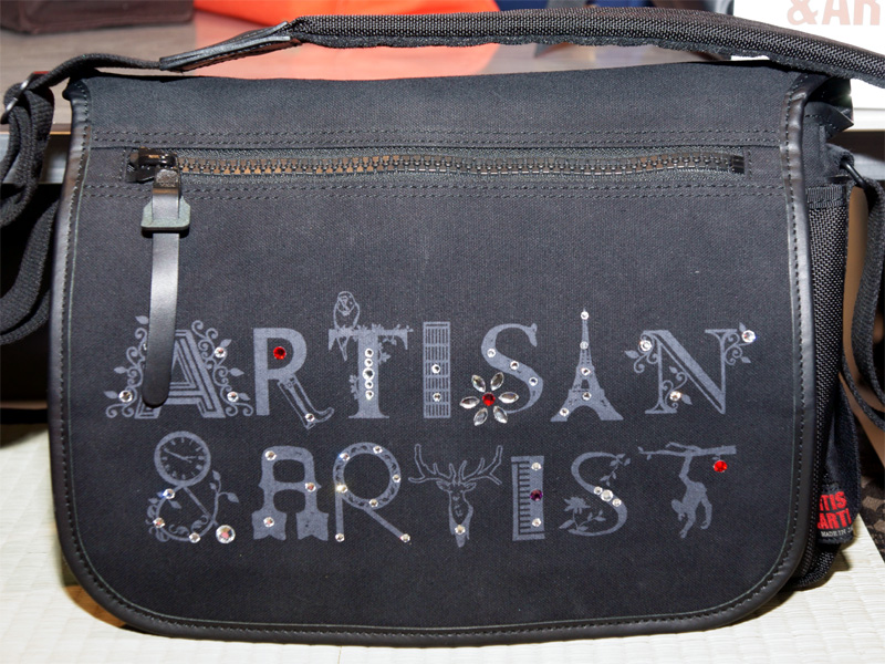 <b>前面にスワロフスキークリスタルの装飾を配したACAMカメラバッグを展示</b>