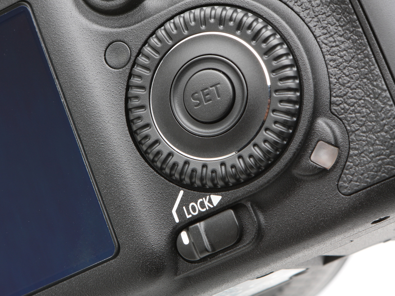 <b>画面中央下はサブ電子ダイヤル専用となったスイッチ。サブ電子ダイヤルはこれまでよりもかなり右に寄った位置に配置される。その斜め左上の丸いボタンのようなものは液晶モニターの明るさを調整するための外光センサー</b>