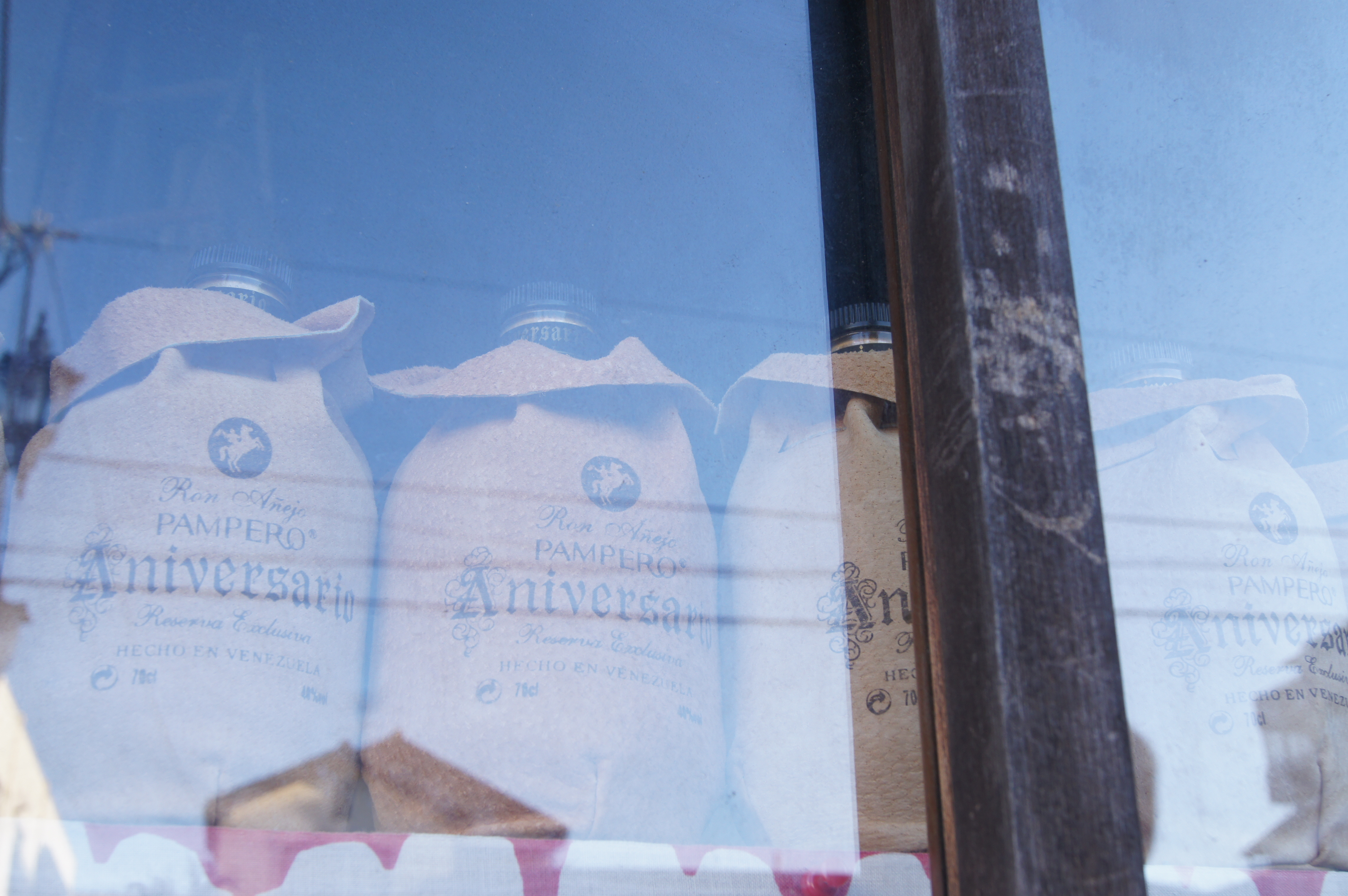 <b>以前にも撮ったことのある、窓辺に並べられた革袋入りのボトル。調べてみたらベネズエラの代表的なラム酒なのだそうな<br>α550 / DT 18-55mm F3.5-5.6 SAM / 4,592×3,056 / 1/30秒 / F8 / +0.7EV / ISO200 / WB:太陽光 / 28mm（42mm相当）</b>