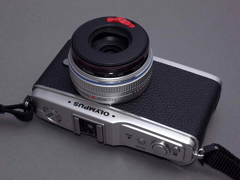 <b>キャップに内蔵されたレンズバリアは、赤いスイッチをスライドするとワンタッチで開く。ただしこのキャップの開口径が小さいので、M.ZUIKO DIGITAL 14-42mm F3.5-5.6のような標準ズームに装着すると画面がけられてしまう</b>