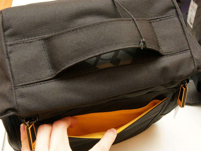 <b>フラップ上部にハンドルを装備。背面にもジッパー式ポケットを備える</b>