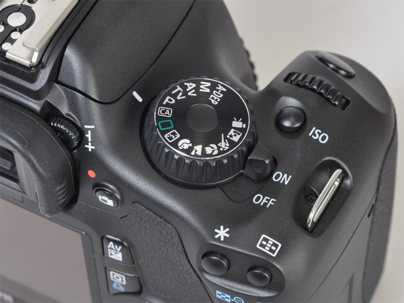 <b>シャッターボタン周りの配置はEOS Kiss X3と同様。モードダイヤルの印字は白抜きに</b>