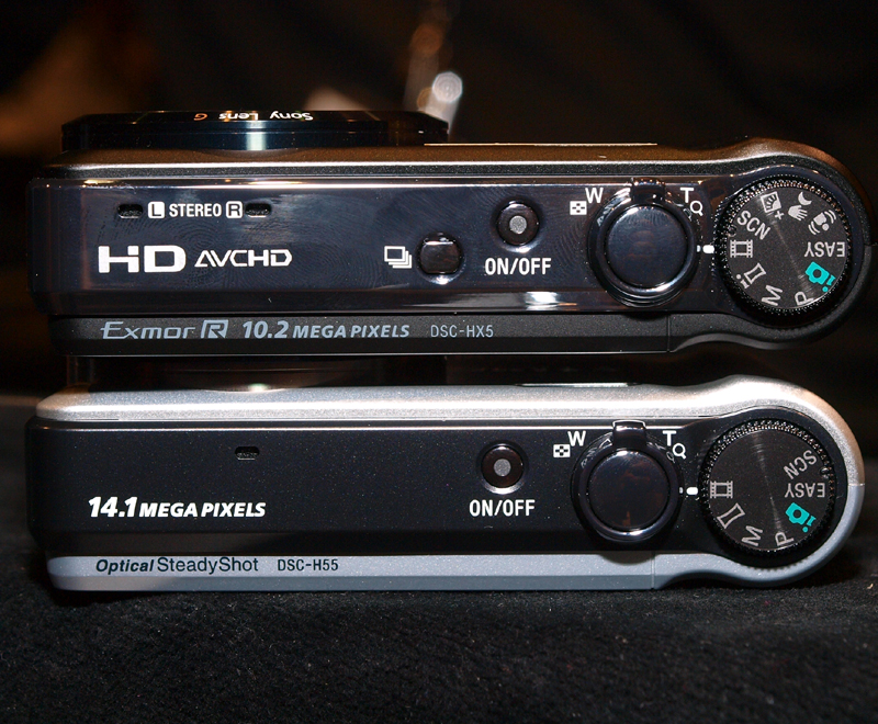 <b>サイバーショットDSC-H55（下）とサイバーショットDSC-HX5V（上）の上部の比較。DSC-H55は、ステレオマイク、連写、ブラケットボタンなどが省略されているのがわかる</b>
