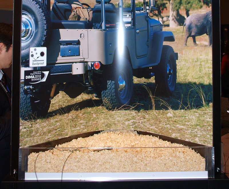 <b>木屑の中に埋もれたサイバーショットDSC-TX5。防塵性能を視覚化したコーナーで</b>