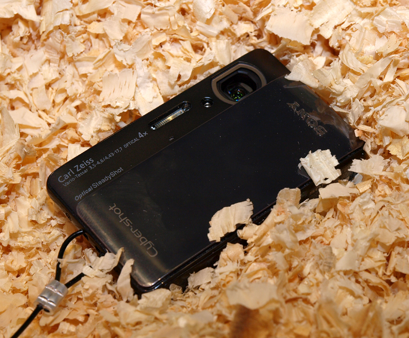 <b>木屑の中に埋もれたサイバーショットDSC-TX5。防塵性能を視覚化したコーナーで</b>