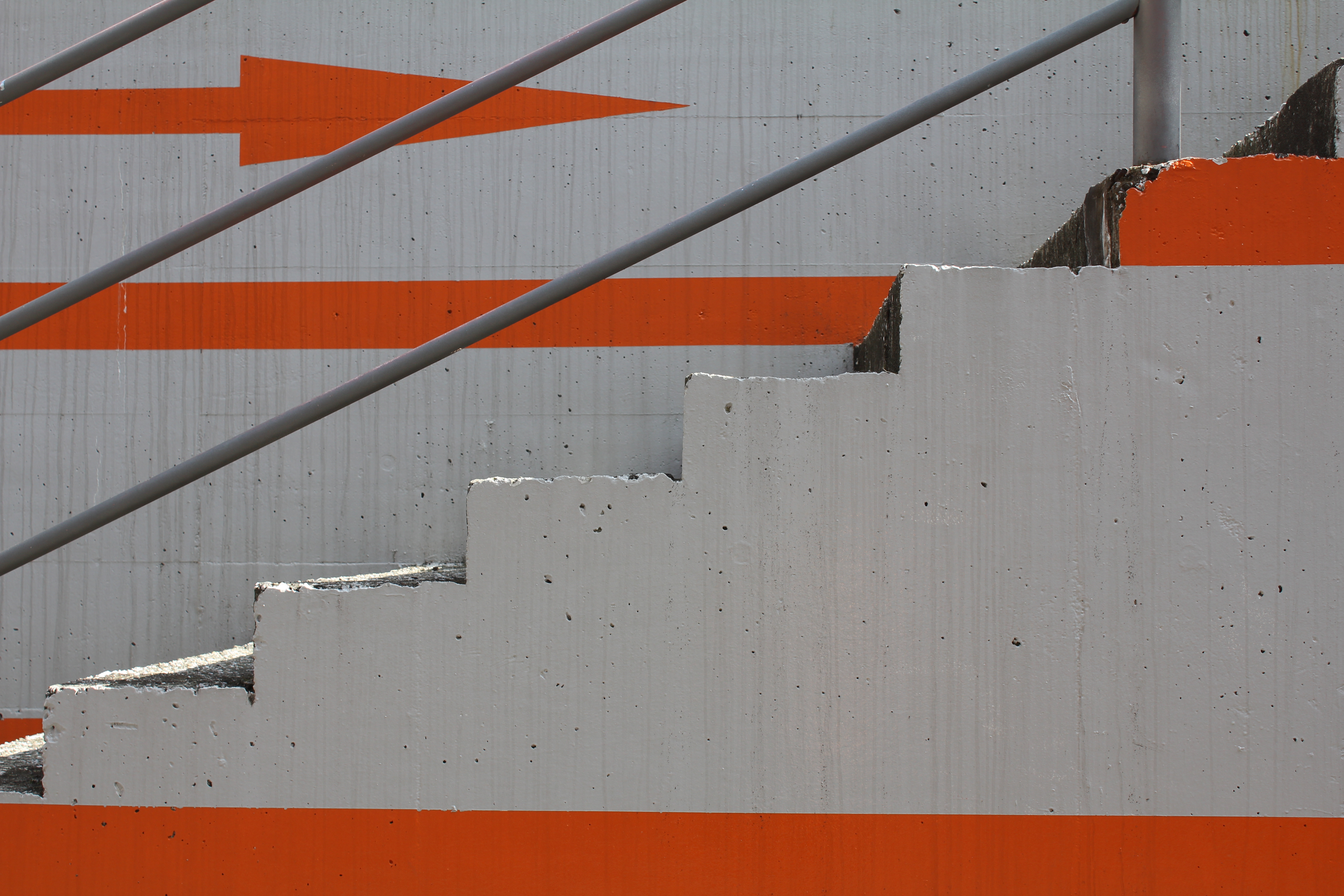 <b>よこはまコスモワールドに渡る橋の下の通路。壁に描かれているオレンジ色の矢印が何を意味しているかは謎である<br>EOS Kiss X4 / EF-S 18-55mm F3.5-5.6 IS / 5,184×3,456 / 1/60秒 / F8 / ＋0.3EV / ISO100 / WB:オート / 34mm</b>