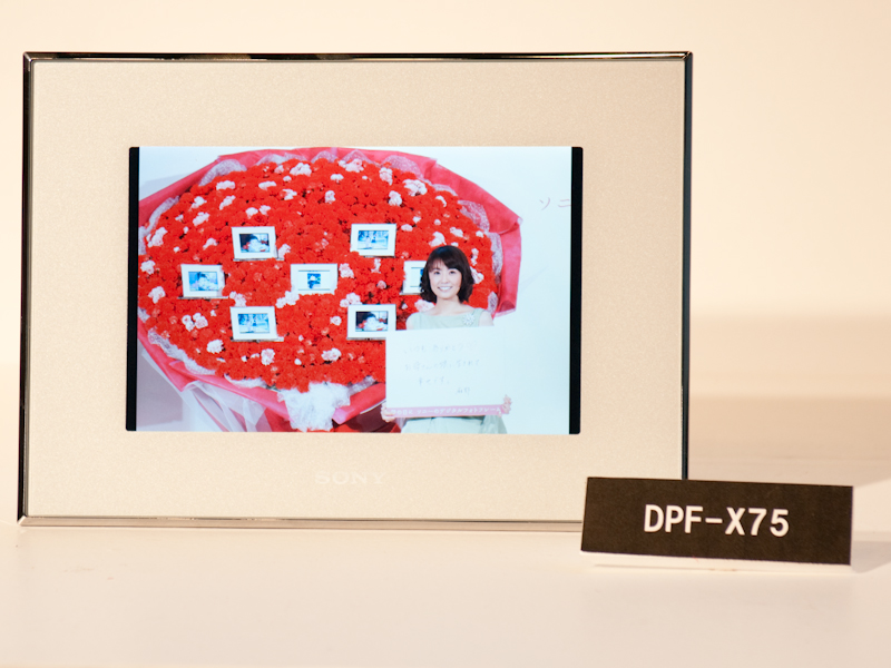 <b>母へのメッセージを書いたボードを持って写真に写る小林さん。デジタルフォトフレームは実際に小林さんの母に届けられるという</b>