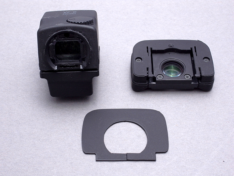 <b>0.7mm塩ビ板をカットして、オリジナルパーツ(手前）を制作。内側の穴は、VF-2のアイカップ取り付け部（直径21mm）に合わせている。外形はマグニファイアーアイカップアイカップに合わせている。下部に切れ目を1カ所入れている</b>