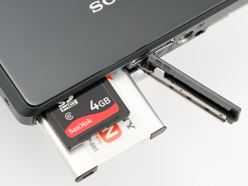 <b>1スロットでメモリースティックデュオとSDカードの両方に対応。電源のNP-BN1は薄型で容量も控え目。できれば予備も用意したい</b>