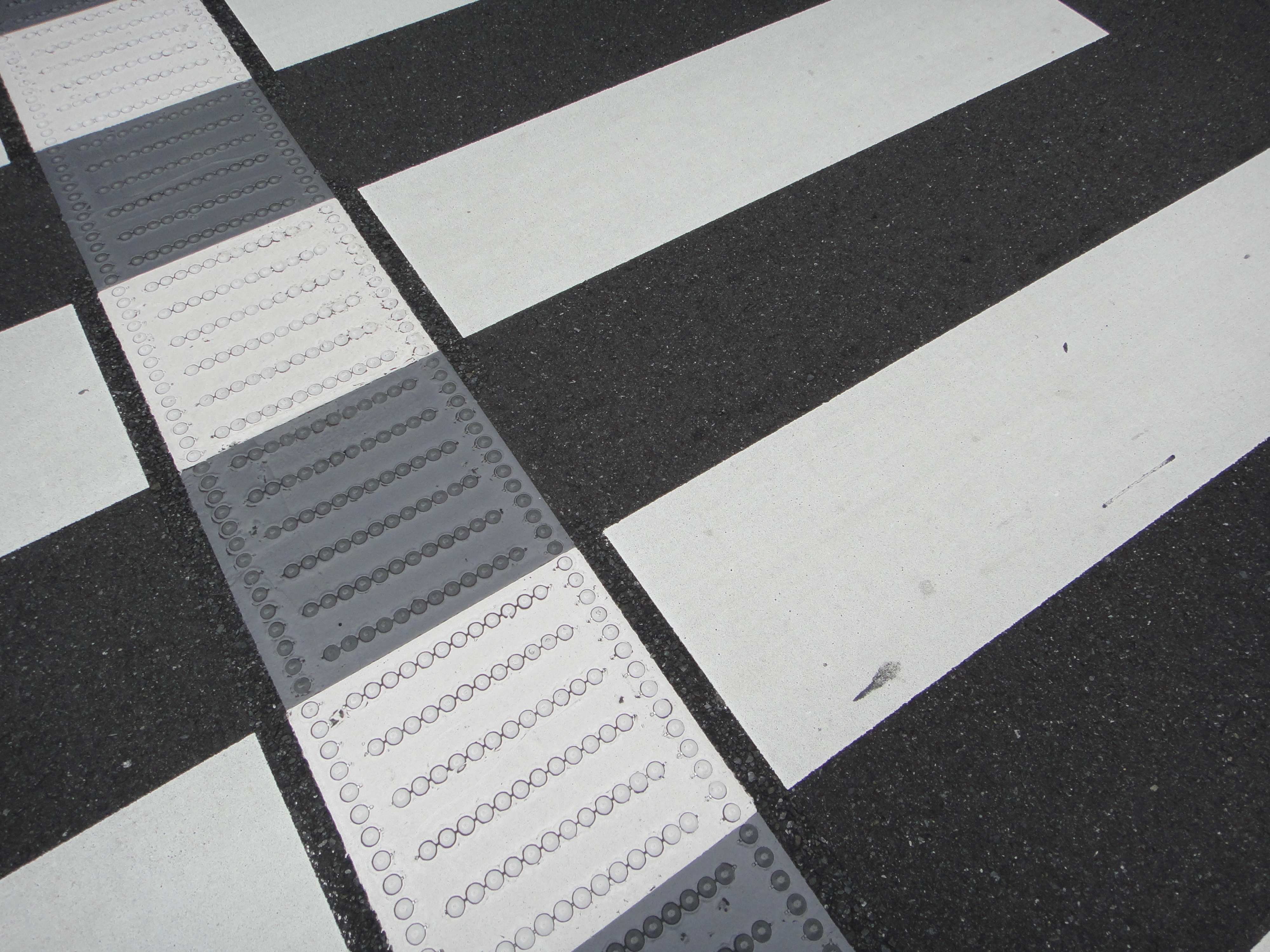 <b>横断歩道の点字ブロックはめずらしいと思ったら、最近増えてきているらしい。色が白黒なのは自動車の運転手を驚かせないためだとか<br>4,000×3,000 / 1/640秒 / F4.5 / 0EV / ISO125 / WB:オート / 4.43mm（25mm相当）</b>
