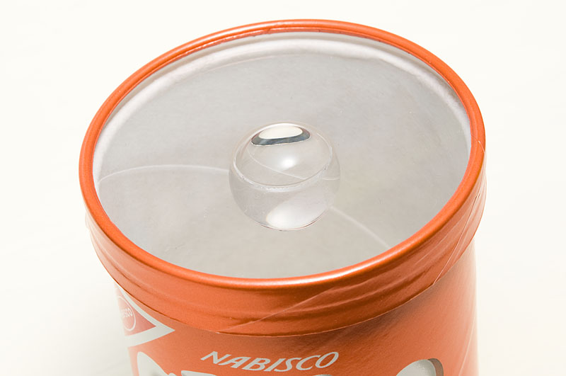 <b>アクリル製の円板に穴を空け、アクリル製の透明球を接着して作った宙玉レンズ。お菓子の空き箱やステップアップリングを使って、カメラのレンズに装着して使用する</b>