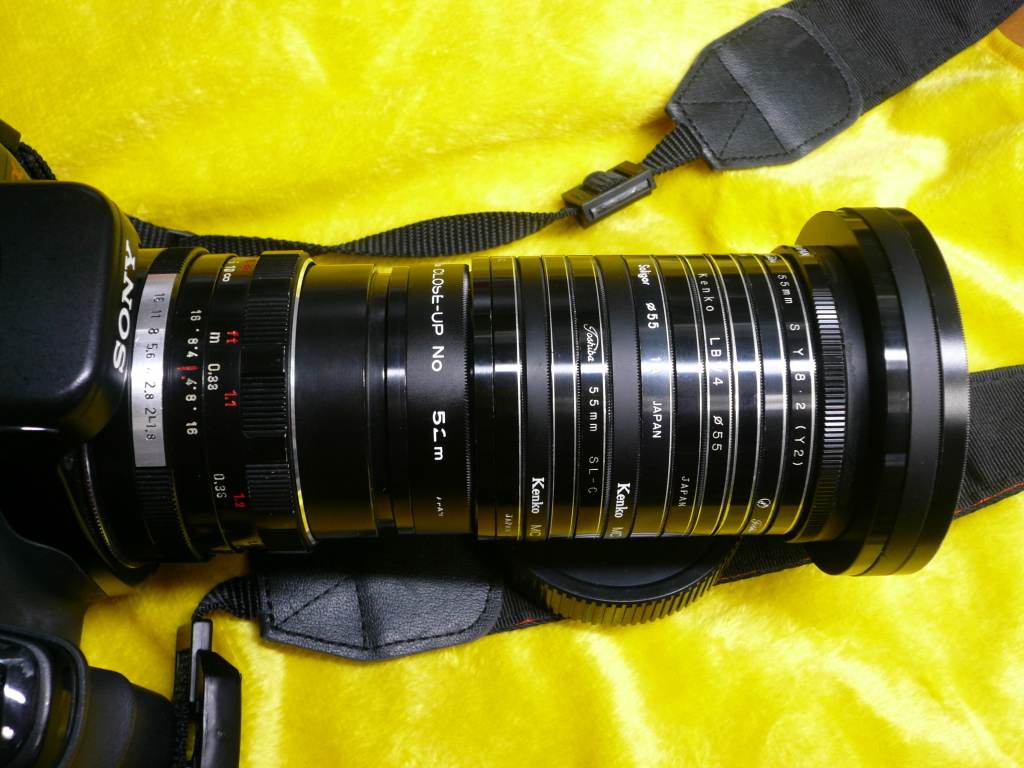 <b>和光のKOBAさんの宙玉レンズ。α100+ペンタコン50mm F1.8に装着。幾重にも連なるのは、ガラスを抜いたフィルターの枠。フィルターの枚数を変えることにより筒の長さが調整できる。中古カメラ店（我楽多屋）で1枚50円で買ったものだそうだ</b>