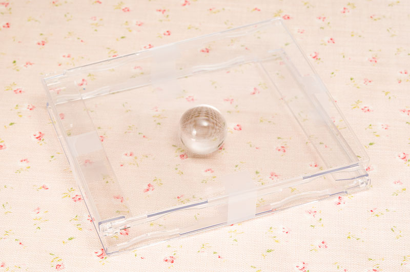 <b>CDケース2つをバラし、透明のビー玉を挟んでテープで留めただけのもの。レンズに装着せずに立てて置いて撮影をしてもいい</b>