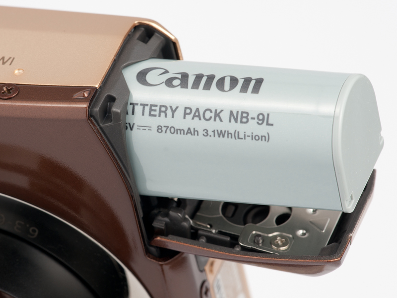 <b>バッテリー室は左手側にある。新型のリチウムイオン電池NB-9Lは容量870mAh。CIPA基準の撮影可能コマ数は150コマ</b>
