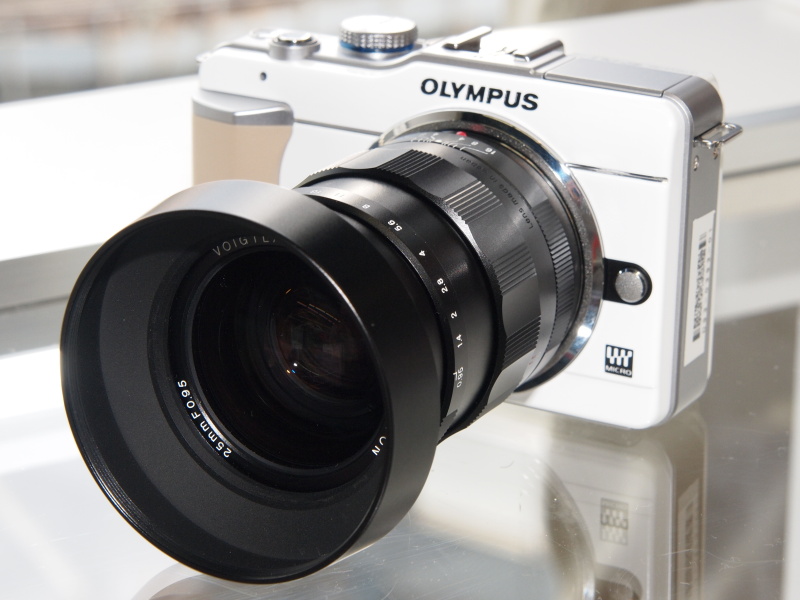 <b>オリンパス「Photo Festa[Pro-Style]」に展示していたNOKTON 25mm F0.95。たまたま私の所有カラーと同じE-PL1があったため、見た目のマッチングも確認済み。左は付属のフード装着時の様子</b>