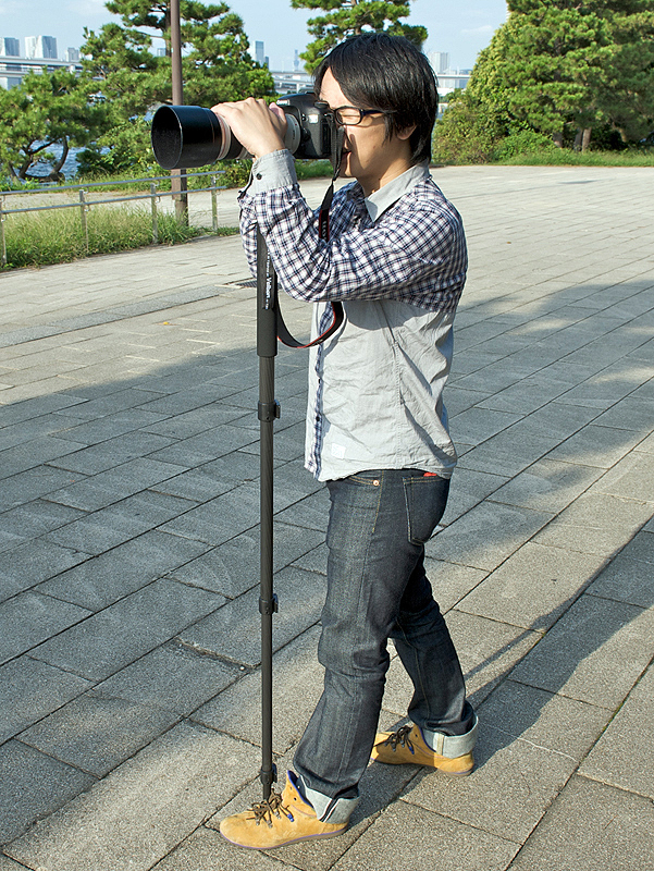 <b>場合によっては、一脚の脚を自分の足で押えるようにすると安定する。実際にこの構え方をするプロカメラマンもいる。靴の内側のへこんでいるところに合わせるのがポイントだ</b>