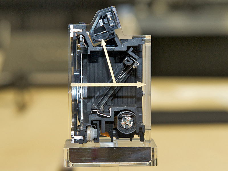 <b>α55のミラーボックス（側面から見たカットモデル）。マウント（左）から入った光は斜めに配置したトランスルーセントミラー（透過ミラー）で、上部の位相差AFセンサーと右の撮像素子に分光される</b>