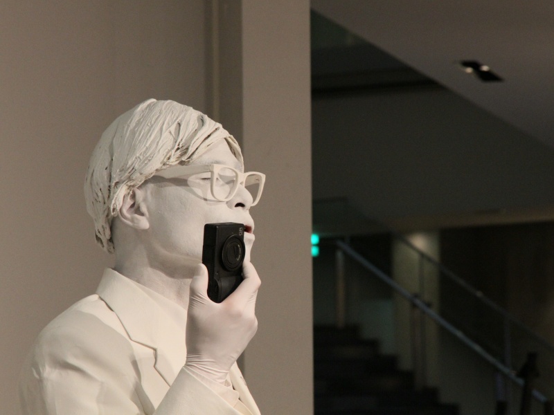 <b>会場に現れた全身真っ白なパフォーマーが来場者の注目を集めていた</b>