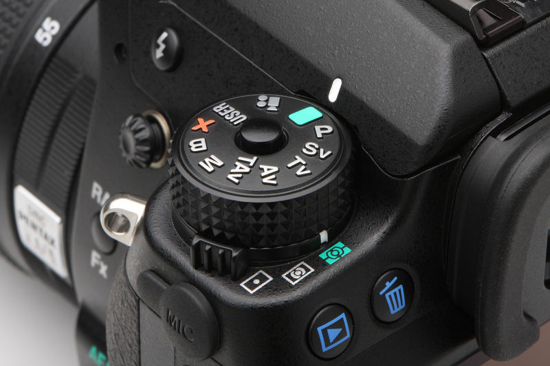 <b>K-7にくらべ少しだけ背の高くなった撮影モードダイヤル。操作感も向上している。ダイヤルの文字やアイコンは浮き出し加工が施されており、視認性はたいへんよい</b>