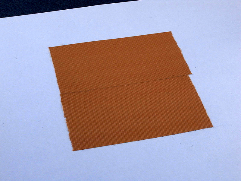 <b>さて、ゴムをどうやって塗るかを考え、治具の製作を思いついた。まず、コピー用紙に短く切ったガムテープを2列貼り付ける。このあとガムテープ以外の周囲をカットする</b>