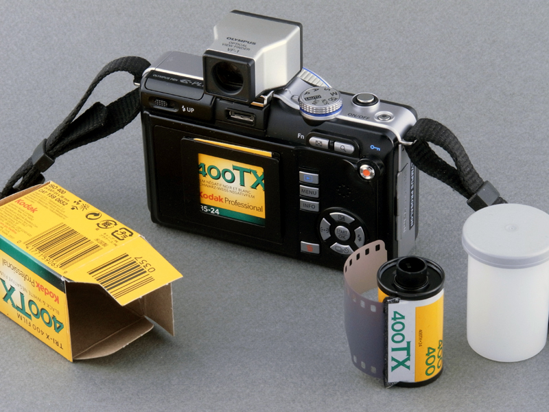 <b>背面のホルダーにフタを差し込むと、まるでフィルムカメラの気分になる。傍らに置いたフィルムはもちろん無関係だが（笑）、E-PL1はもともとフィルムカメラっぽいデザインなので違和感がない</b>