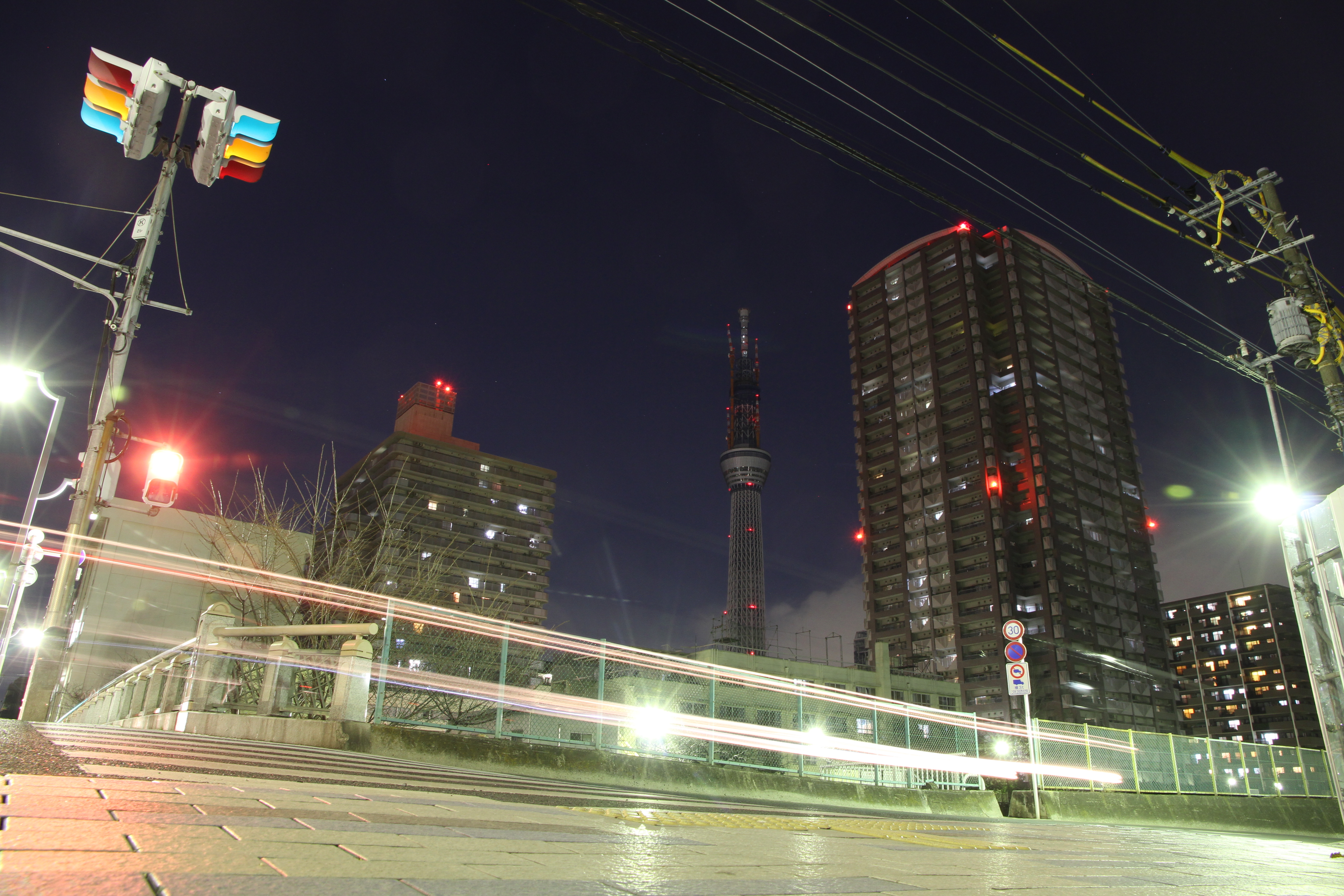 <b>この撮影場所は昼間、工事用車両が出入りしているので夜訪れた。この付近で東京スカイツリーが広く入る位置は少なく、また撮影できるスペースも限られてくる。何度か撮影して10秒間の露光中に信号が3つとも点灯している写真を選んだ。EOS 7D / EF-S 15-85mm F3.5-5.6 IS USM / 5,184×3,456 / 10秒 / F10 / -1EV / ISO400 / 絞り優先 / WB:オート / 15mm / 19:02</b>