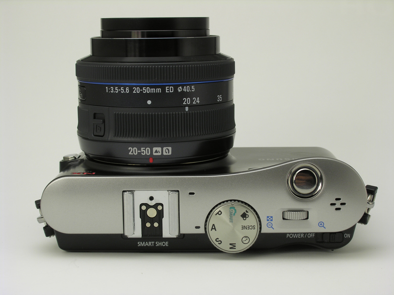 <b>ボディ上面に、シャッターボタン、モードダイヤル、電子ダイヤル、一段下がった部分に電源スイッチがある。アクセサリーシューはスマートシューという名称で、ボディ背面側にEVF用コネクターを装備。ストロボ用接点は、NXシリーズ専用規格のため一眼レフカメラのGXシリーズとの互換性はない</b>