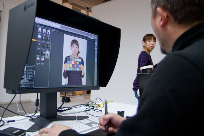 <b>MacBookProに繋がれているのはカラーキャリブレーションが施されたEIZOの液晶モニター。アシスタントの萩さんにカラーチャートを持たせてテスト撮影。「昔で云う、ポラチェックみたいなもんですね（笑）」。カラー調正やホワイトバランスを完璧にチェックしてから撮影に入る</b>
