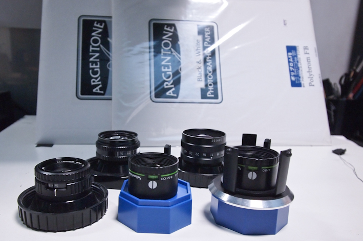 <b>35㎜判～4×5サイズまでの各対応の引き伸ばしレンズ群。ELニッコールとローデンシュトック製品。後ろにあるのは今気に入ってるというFORTE社のARGENTONEペーパー</b>