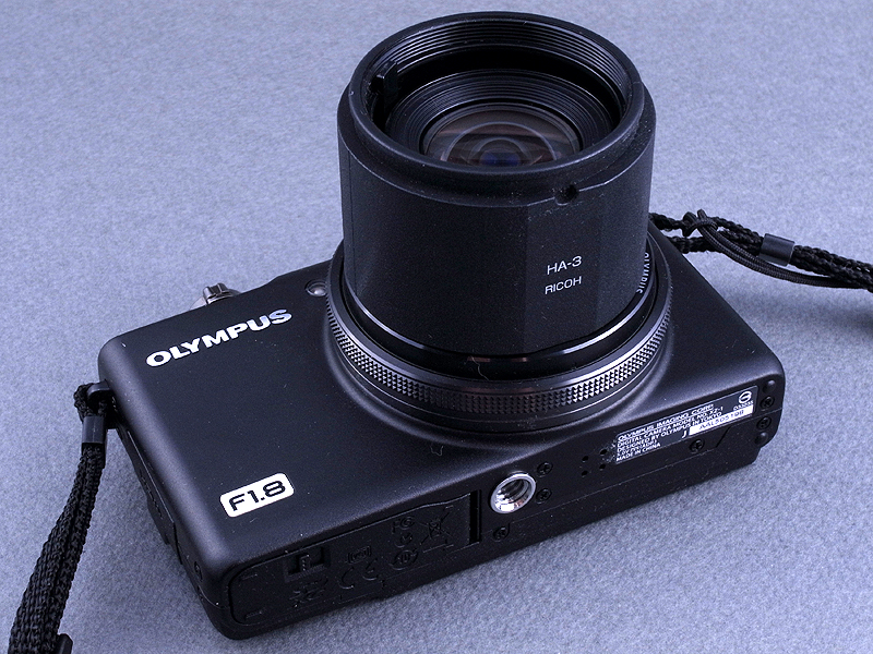 <b>とりあえず電源ONしたXZ-1に、リコー「GXR」のS10（RICOH LENS S10 24-72mm F2.5-4.4 VC）用のアダプターリング「HA-3」を被せてみる。もちろん被せただけで固定することはできない。しかしここで“切り貼り”の勘によってハッと閃く物があった（笑）</b>