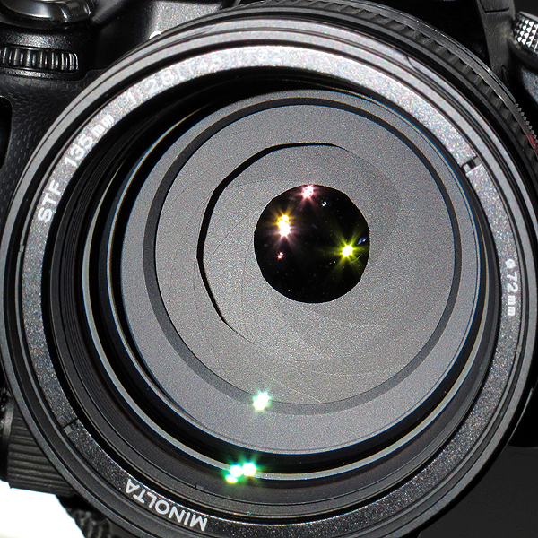 <b>ミノルタSTF 135/2.8[T4.5]の手動絞り（手前）と自動絞り（奧）。手動絞りはT6.7まで絞り込んだときにもっとも美しい形状となる。写真はF5.6付近の絞り形状。奥に見えるのが自動絞りで、絞りリングを［A］にセットしたときに、自動絞りが動作する</b>
