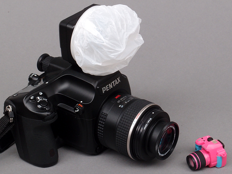 <b>すべてのセットを装着すると、このような状態になる。片手でラクラク……とまでは行かないが、かなり軽量化された。ちなみに645Dに外部ストロボを装着した場合、シャッター速度1/125秒以上は外部ストロボが発光しない“親切設計”になっている。しかし<a href="http://dc.watch.impress.co.jp/docs/review/labo/20091015_318745.html"><u>以前の記事に書いたように</u></a>、シンクロ速度の上限を超えても撮影できるシチュエーションがあるので、このあたりはユーザーの自己責任に任せて欲しいとぼくは思う</b>