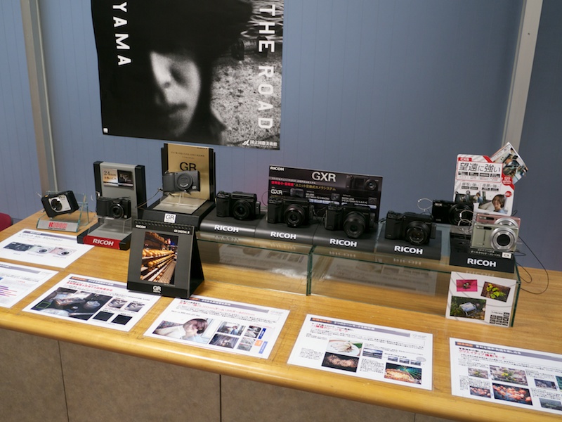 <b>サービスセンター内の現行品展示コーナー。GR LENS A12 28mm F2.5やCX5もある</b>