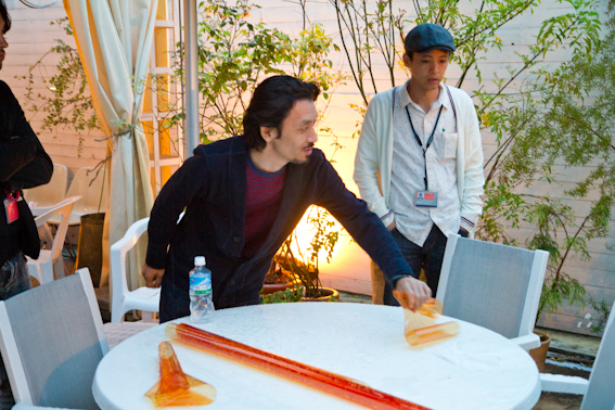 <b>雨が降る中、ライトにカラーフィルターを取り付けたり、飾り付けの明るさを大勢のスタッフで調整してからテスト撮影。春といってもまだ寒いので上着とストーブは必需品なのが屋外撮影の厳しいところ</b>