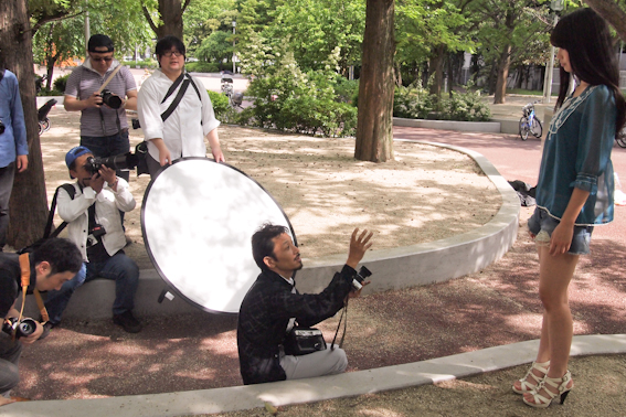 <b>休日に土屋先生の指導ぶりを見学させていただいたのは、彼が担当しているオリンパスズイコ－アカデミーの撮影実習。この日は10名ほどの生徒さんたちが都内の公園に集まっていた。撮影のポイントを説明したら早速みなさんのレンズ群がモデルさんに向けて一斉砲撃を開始したのには驚いた（笑）</b>