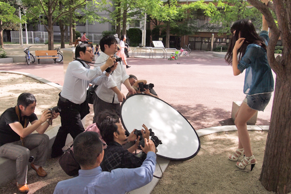 <b>休日に土屋先生の指導ぶりを見学させていただいたのは、彼が担当しているオリンパスズイコ－アカデミーの撮影実習。この日は10名ほどの生徒さんたちが都内の公園に集まっていた。撮影のポイントを説明したら早速みなさんのレンズ群がモデルさんに向けて一斉砲撃を開始したのには驚いた（笑）</b>