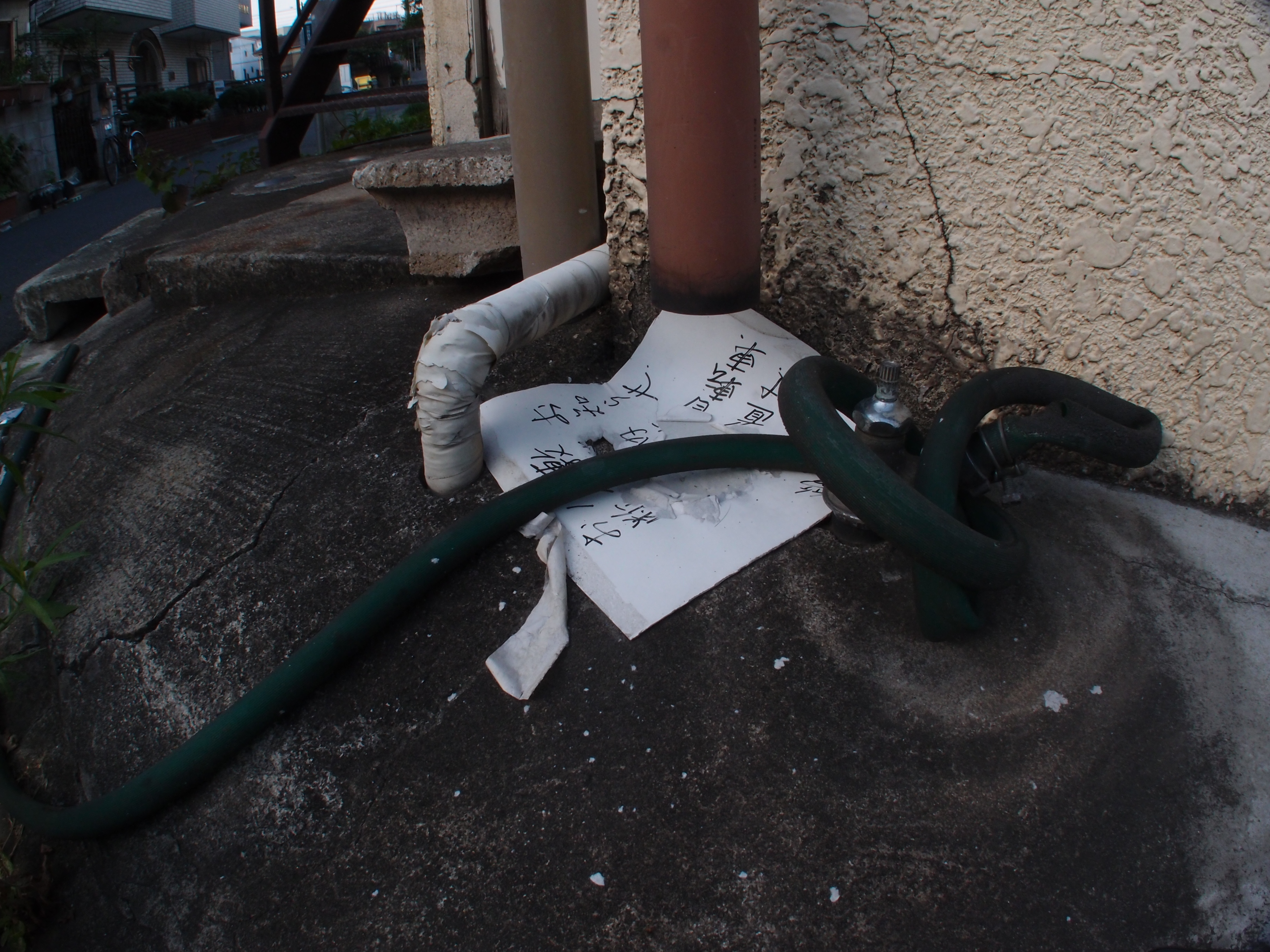 <b>雨樋の下に張り紙に雨水が落ちている。単にそれだけのことだが、落下する水によって張り紙を変容させる“作品製造装置”に見えなくもない（笑）。XZ-1 + FCON-P01 / 3,648×2,736 / 1/40秒 / F8 / -0.7EV / ISO125 / 絞り優先AE / WB:オート / 6mm</b>