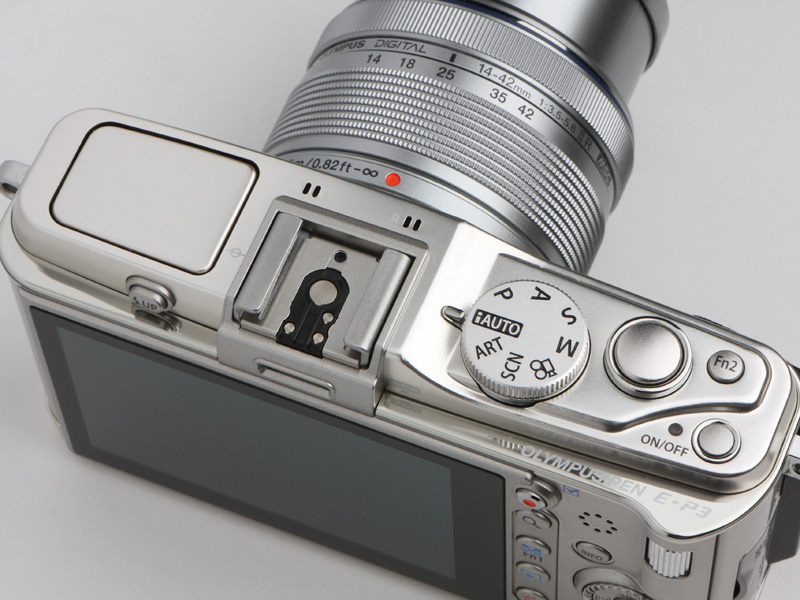 <b>ストロボを内蔵したため、ボタン、ダイヤル類のレイアウトが変更になっている。特にモードダイヤルは、ホットシューを挟んでこれまで左側にあったが、E-P3では一般的な右側に置かれる</b>