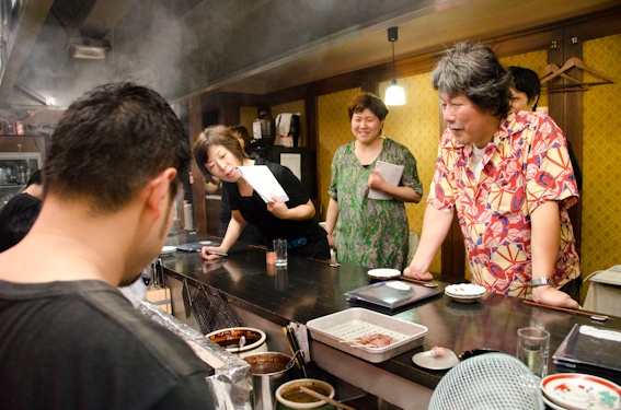<b>再び、焼きの進行や煙りの具合を見ながら店内の風景カットのアングルを決めて三脚セット。三脚はジッツオのカーボンに自由雲台＆クイックシュー付きが軽くてコンパクト。そして狭い店内でも取り回しが便利だ</b>