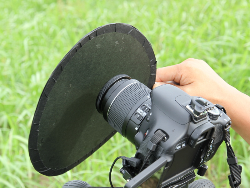 黒い紙を貼ったうちわをレンズの前にかざす