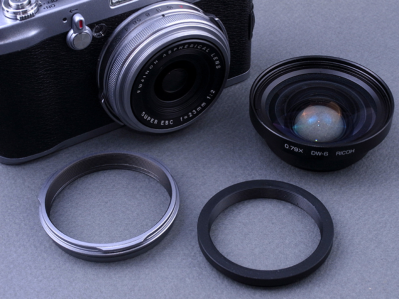 <b>リコー製ワイコン「DW-6」（右）をFinePix X100に装着するには、まずレンズ先端の化粧リングを外して専用のアダプターリング（左）を取り付ける。そして49→43mmのステップダウンリング（中）を介してDW-6を取り付ける</b>