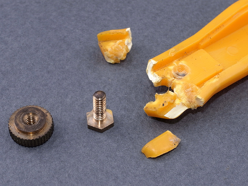 <b>Pカッターの先端部を金づちとポンチを使って割り、埋め込まれたボルトと止めネジを取り出す</b>