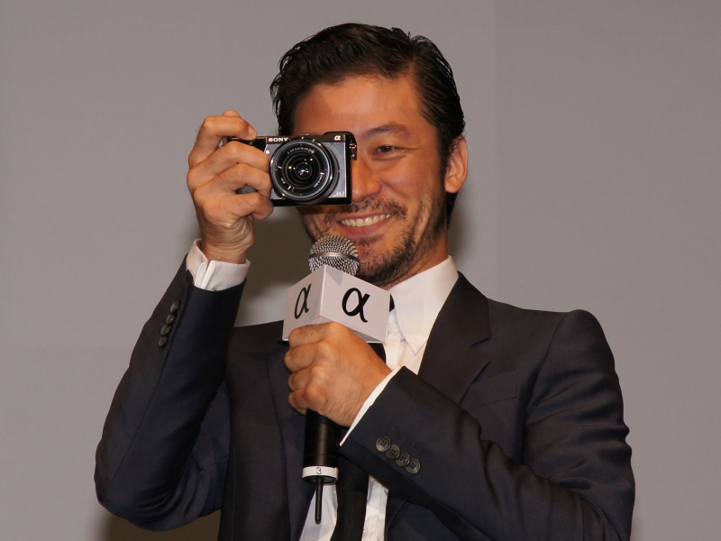 <b>NEX-7を手に、取材陣を撮影する浅野さん。EVFを覗いて「本格的な感じが楽しい」ともコメント</b>