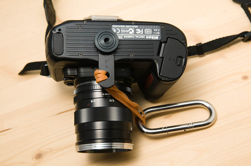 <b>デジタル一眼レフカメラ底部の三脚穴に金属部品を取り付け、ゴムで吊るせるうようにした。しかし、逆さまになってしまうのが問題</b>