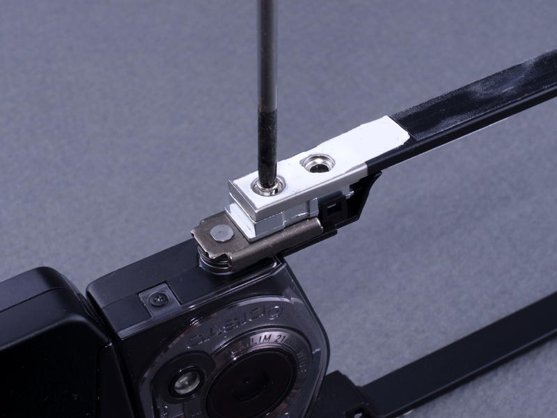 <b>インナーフレームは、白テープの下に隠れたネジでヒンジに固定されていた。テープの接着力は強力なので無理に剥がさず、ドライバーでネジ頭を探り、そのまま捻りながら外した</b>