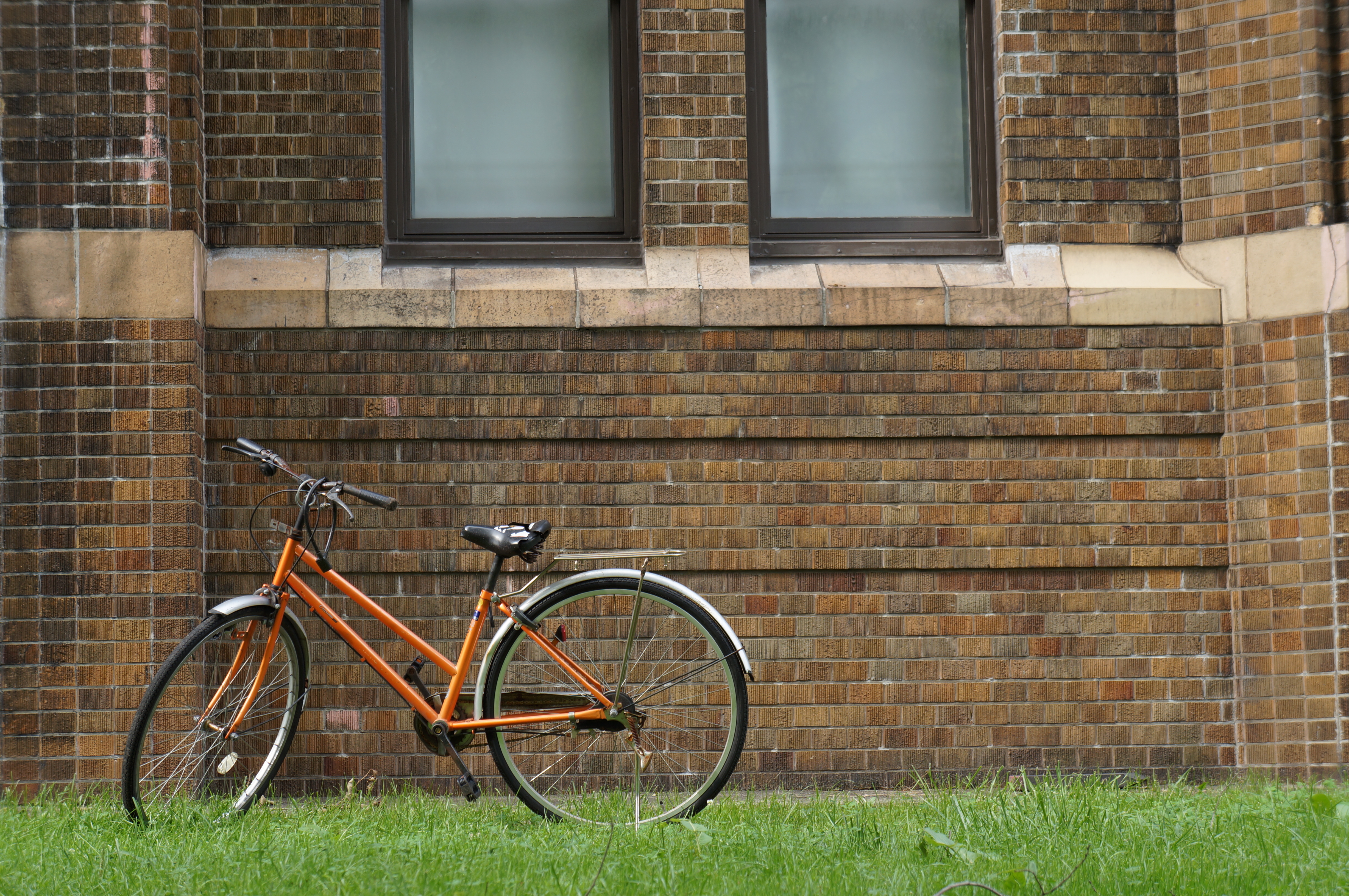 <b>レンガの壁の前にオレンジの自転車。よく見ると、サドルとかすごい壊れ方してますけど。NEX-5N / E 18-55mm F3.5-5.6 OSS / 4,912×3,264 / プログラムAE / 1/60秒 / F5.6 / 0EV / ISO100 / WB:オート / 55mm</b>