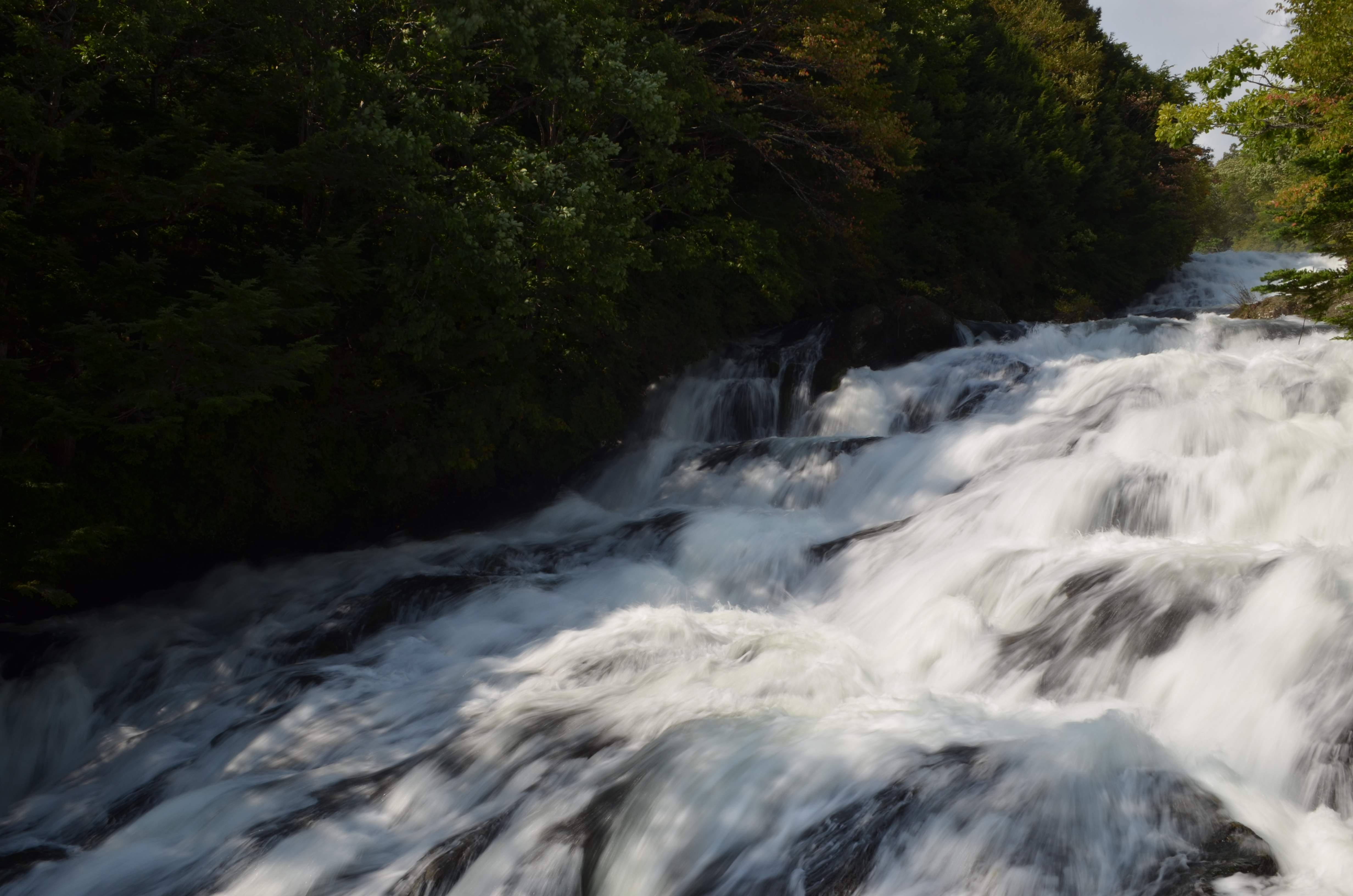 <b>太陽の光を浴びて白く輝く滝の流れを、画面に大きく入れ撮影した。露出補正なし（左）では水の流れのディテールがわかるが、全体的に暗く写ってしまった。そこで+0.7補正（右）で写真全体を明るく撮影した</b>